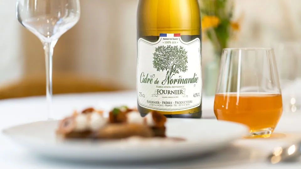 Une bouteille de cidre fournier accompagné d'un plat au restaurant